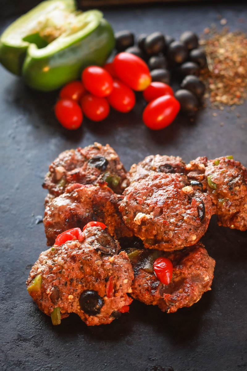 Stuffed hamburgers with fresh tomatoes, peppers, olives, and feta cheese. 