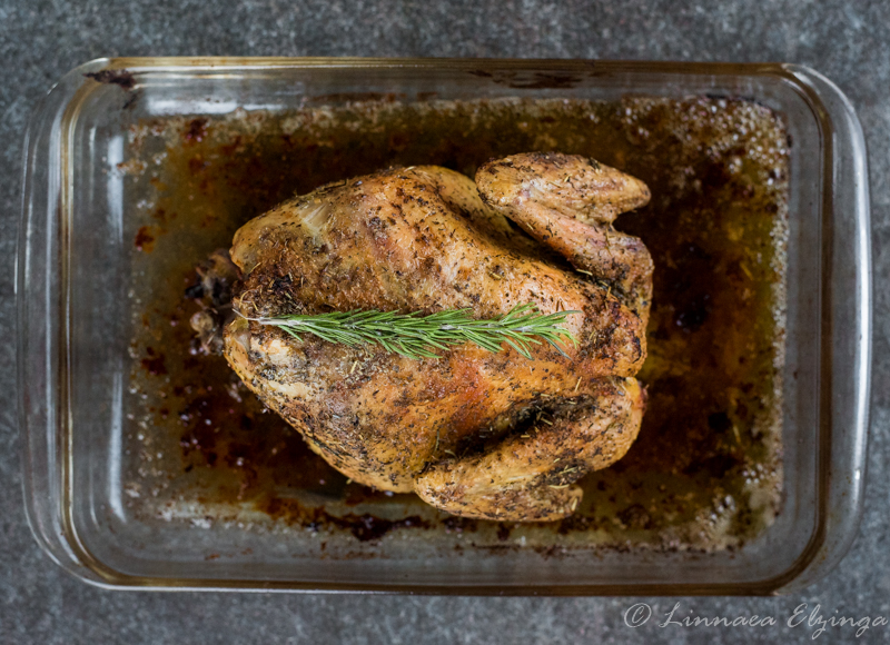 Baked whole chicken with rosemary garnish. 