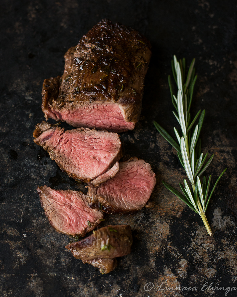 Sliced shoulder tender steak with rosemary garnish. 