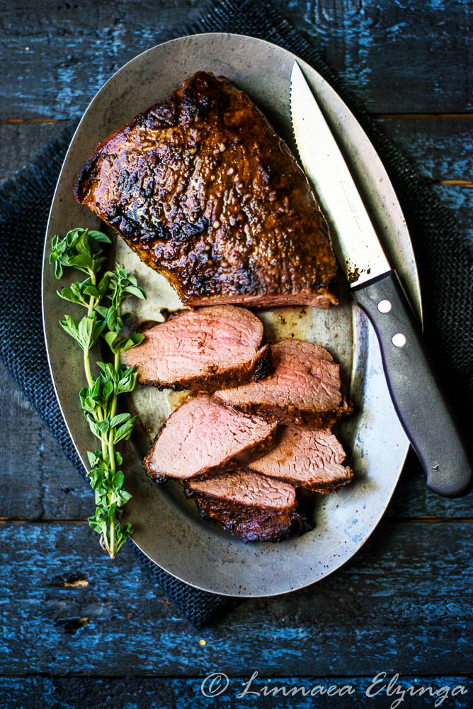 Sliced grilled tri tip roast with basil garnish. 