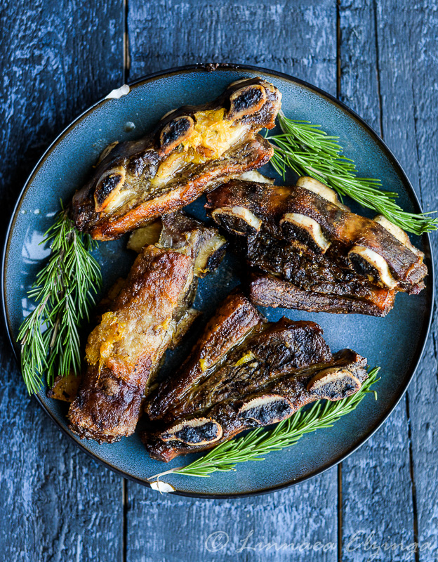 Overview of grass fed organic beef short ribs with rosemary garnish. 