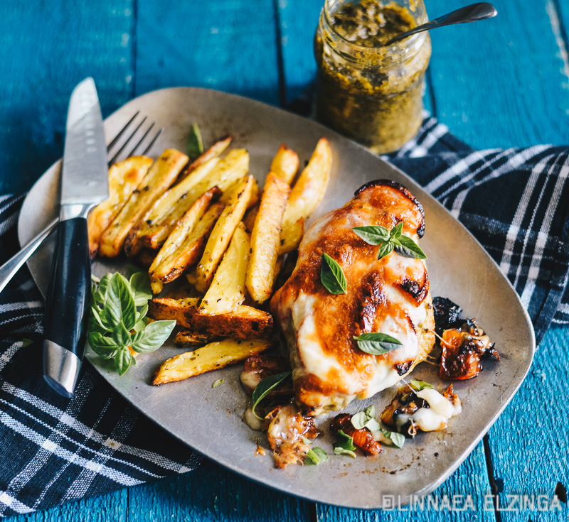 Italian pesto chicken breast with potato fries and basil garnish. 