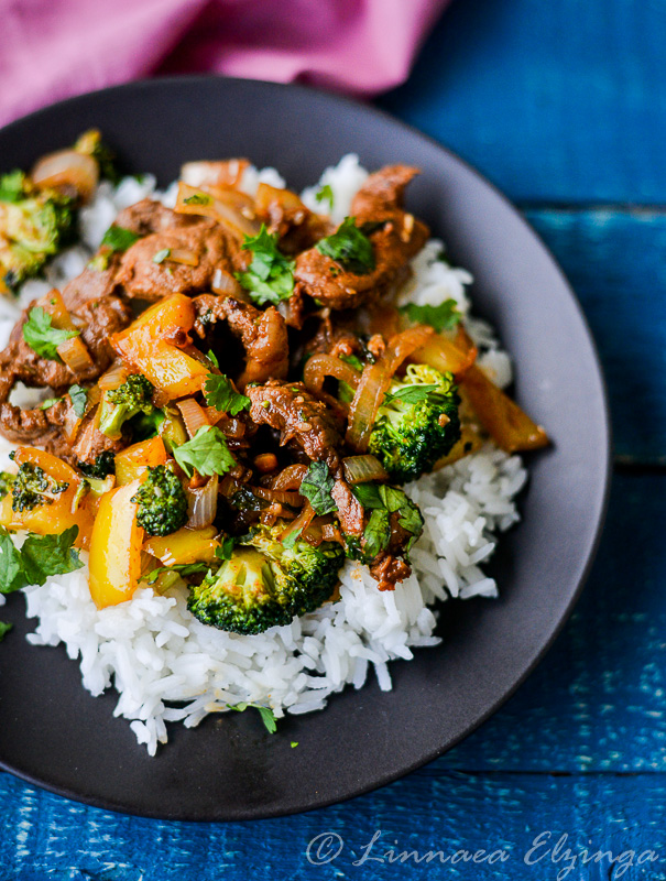 Easy Asian beef stir fry with broccoli, served over rice on a black plate. 
